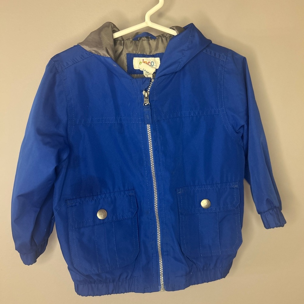 Blue windbreaker jacket with hood and functional pockets.